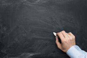 Close up of male hand writing on a blackboard with copy space